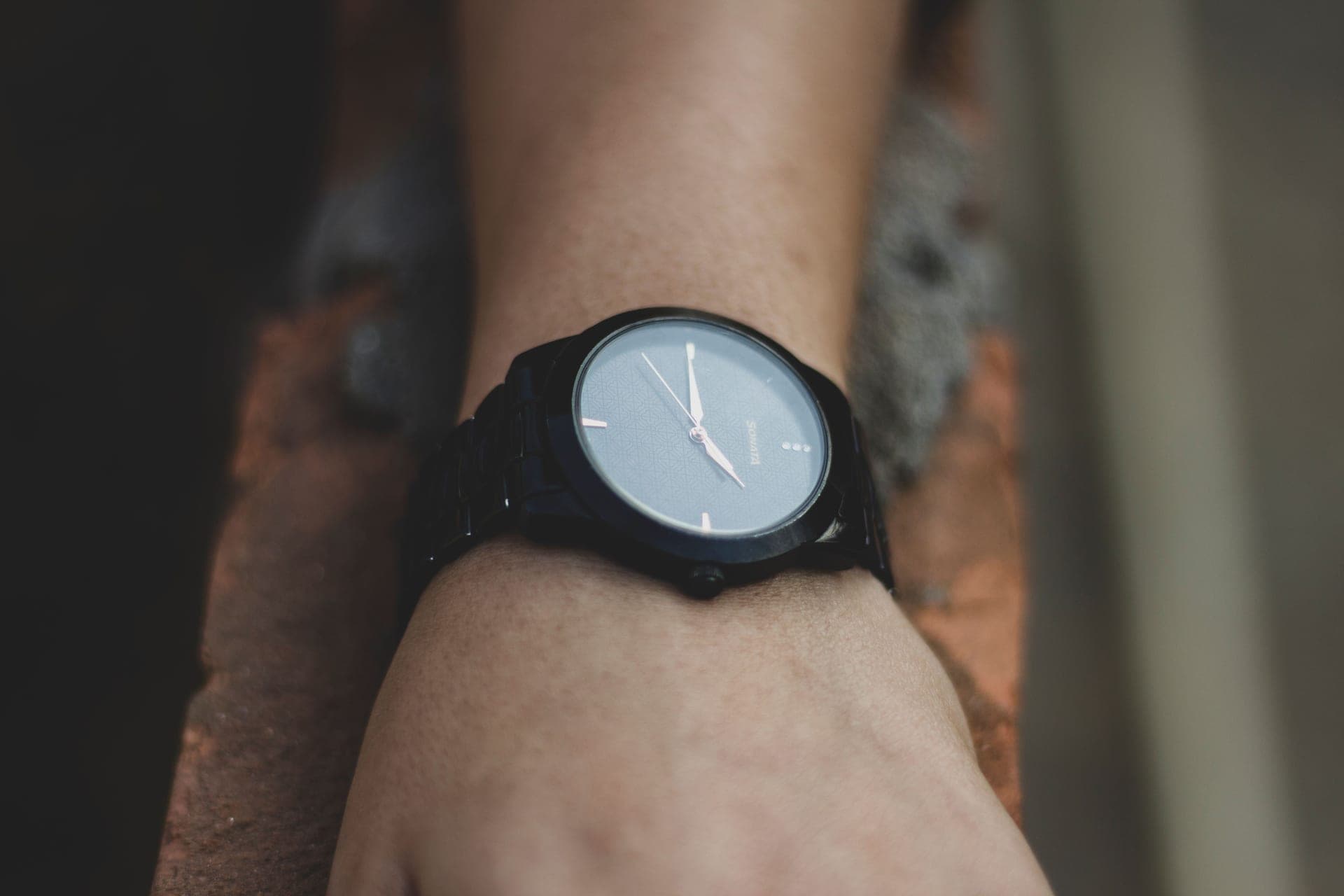 A dress watch worn on a wrist against a soft neutral background